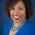 Photo of Rashida Willard, smiling, weating blue sweater and necklace